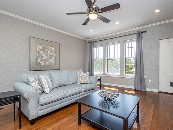 Large, light-filled living room. Windows have blinds and room-darkening curtains that will stay. Door on right goes to large laundry room/closet. There is a small cat/dog door into laundry/closet.