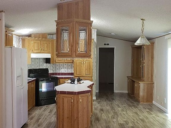 Open concept kitchen/dining and living room areas. Sliding doors with vertical blinds offer natural lighting as needed.