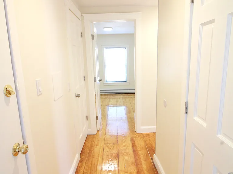 Entrance to apartment with coat closet and washer/dryer on right; bedroom straight ahead.