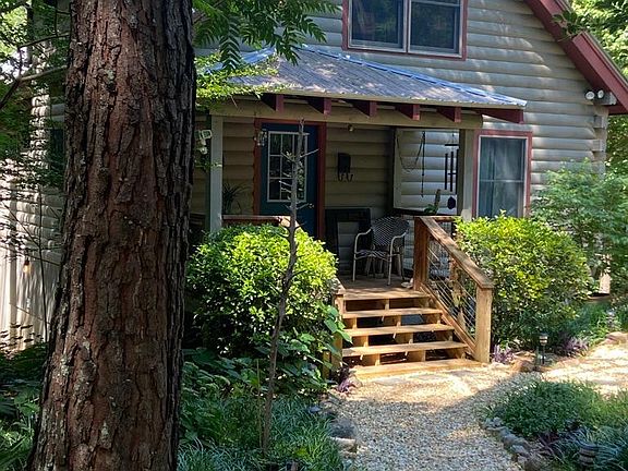 The top windows are for the upstairs bedroom which has an adjoining bathroom with tile shower and an additional loft area. There is a built-in bookcase at the top of the stairs. On the main floor is the porch and door going to the bonus entry room with c