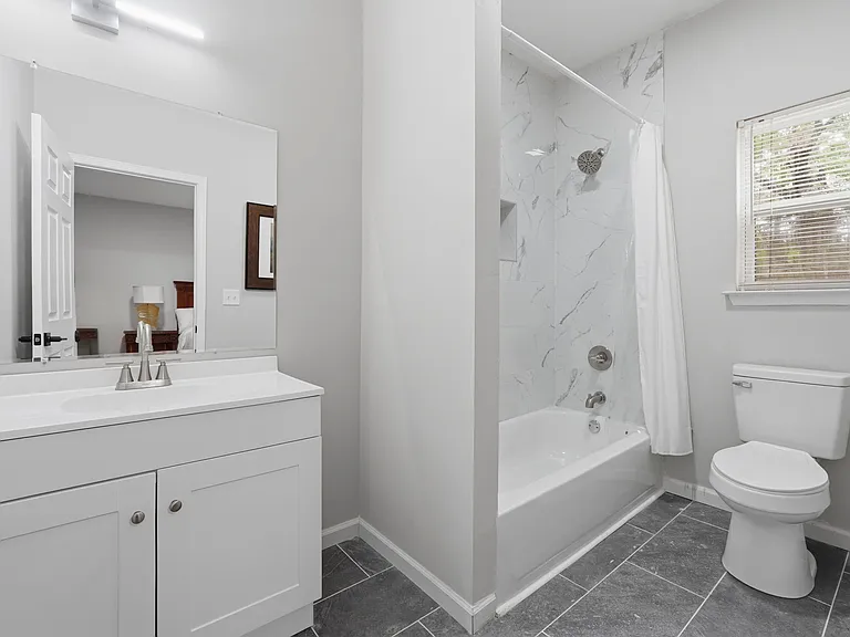 Clean full bath with a wide vanity, large mirror, and tub/shower combo with tile surround plus window for ventilation.