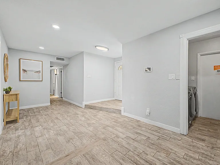 Wide entry hallway with wood-look tile flooring, recessed lighting, and easy access to nearby rooms and laundry area.