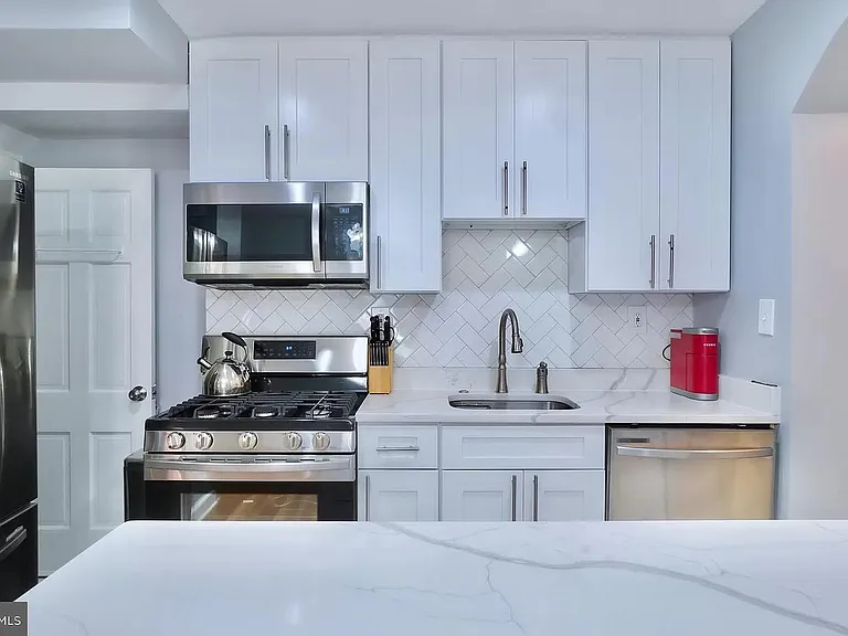 Updated kitchen with stunning stainless steel appliances, white cabinets, solid surface countertops. Bonus pantry area to the right (in the pic)