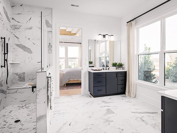 Spa-like primary bath with dual vanities and convenient access to the walk-in closet laundry room