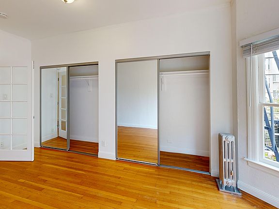 Bright bedroom with wood-like floor and a closet with mirror