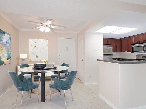 Staged dining area with ceiling fan and kitchen with stainless steal appliances.