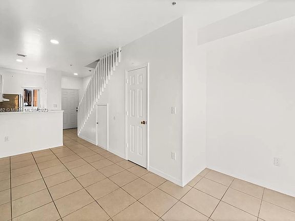 Living Room: Offers a view into the kitchen and has some cracked tiles.