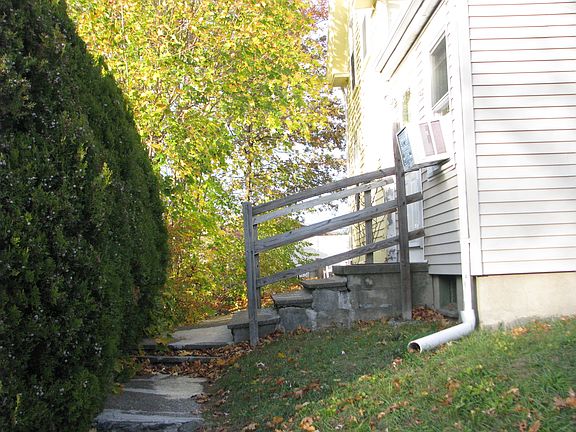 Walkway to apartment with large privacy bushes to the left