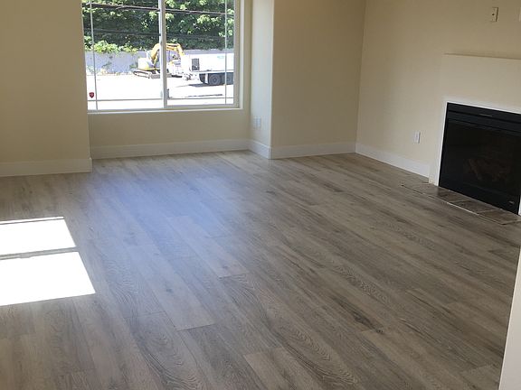 Spacious, bright living room with gas fireplace open to kitchen. New laminate flooring and white millwork throughout.