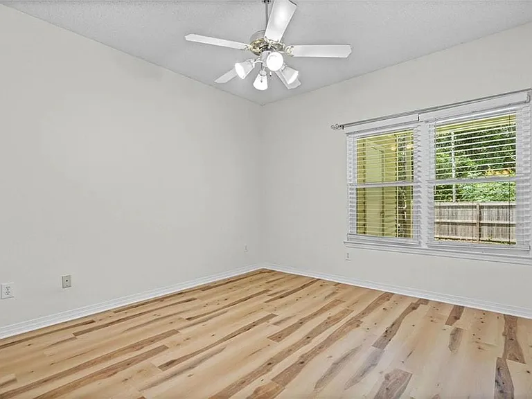 Bright room featuring wood-finish flooring and a white ceiling fan with integrated lighting