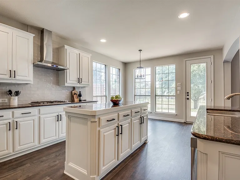Kitchen featuring a central island, white cabinetry with dark hardware, dark countertops, and wood-finish flooring