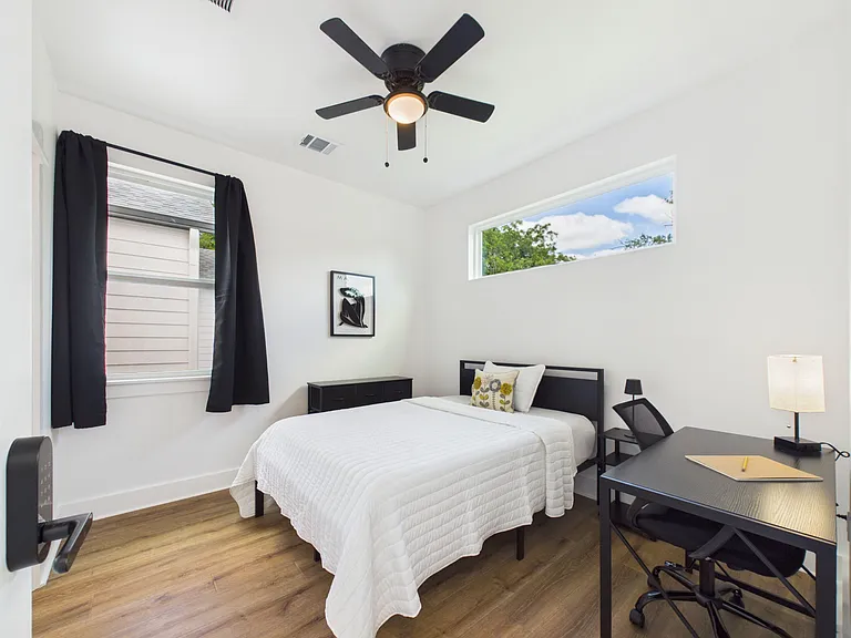 Spacious bedroom with ceiling fan, two windows, and room for a bed plus a work desk for convenient study or remote work.