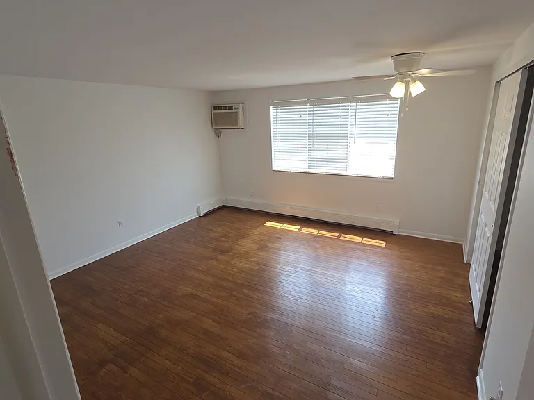 Spacious primary bedroom with hardwood flooring, large window, ceiling fan, and generous closet.