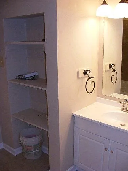 Upstairs full bathroom with storage shelves and separate linen closet to the right of the sink.