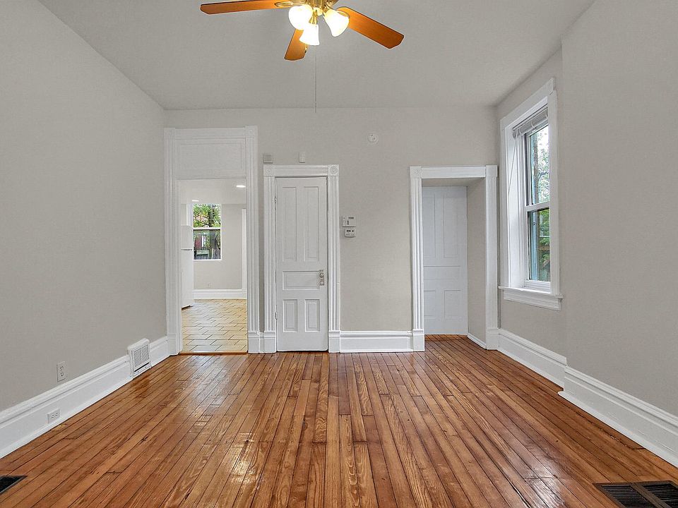 Inviting living room with tall ceilings, beautiful salvaged hardwood floors throughout, oversized windows, original trim, and a ceiling fan.