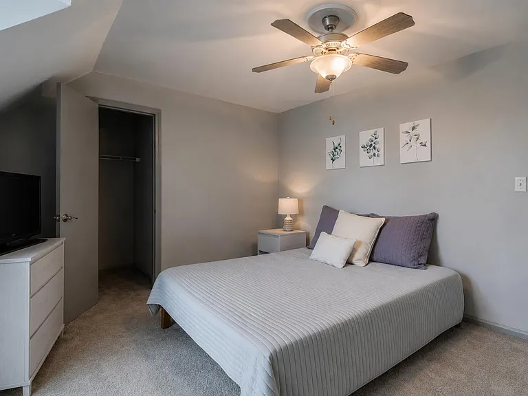 Queen bed, nightstand lighting, ceiling fan, and a closet for convenient storage.