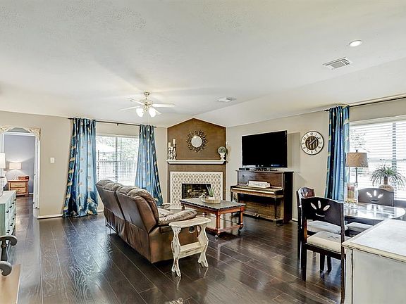 Spacious living room features beautiful floors, neutral paint, a corner fireplace and dining area.