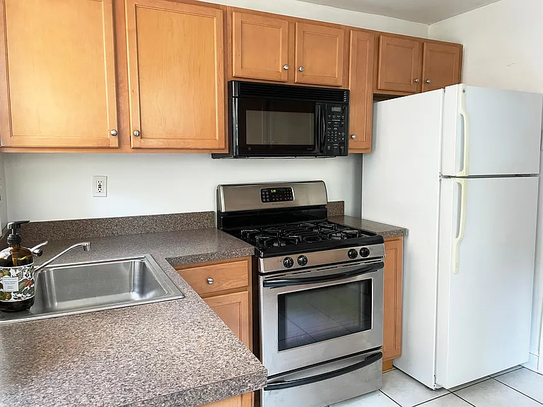 Kitchen equipped with a gas range/oven, new stainless steel refrigerator/freezer (not pictured), garbage disposal, and microwave oven. Access to the private outdoor patio.