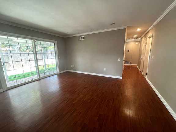 Bright and welcoming front living room featuring abundant natural light and a large sliding glass door that opens to the outdoor entertaining area.