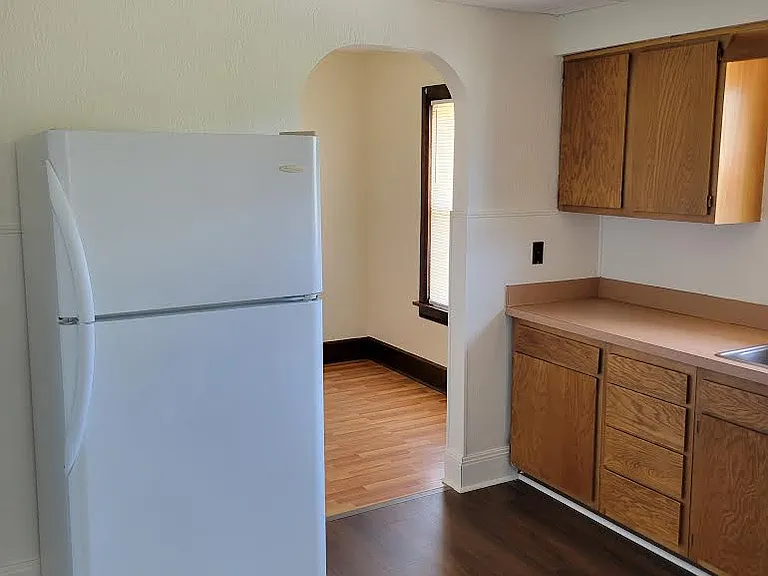 Kitchen leading to breakfast nook and with refrigerator, cabinets and new windows.