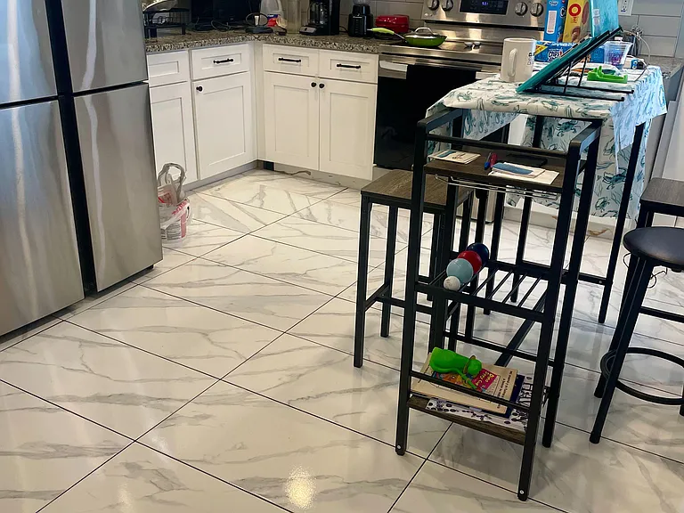 Kitchen with white shaker cabinetry, stainless steel appliances, tile backsplash, and durable tile flooring.