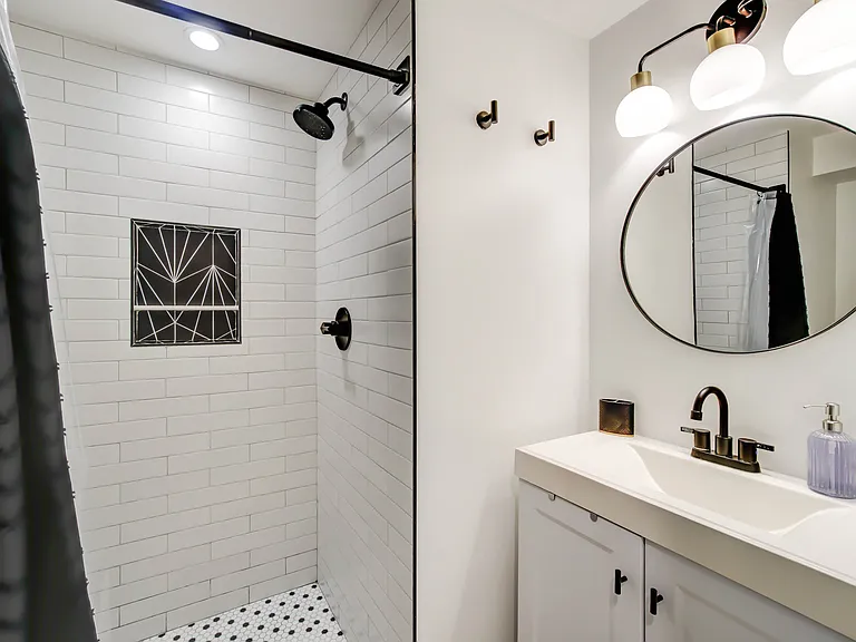 The stylish bathroom features a modern vanity with convenient under-sink storage, blending functionality with a clean, contemporary look.