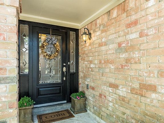 As you approach the brick-lined front porch, you are greeted by the recently painted solid wood door with exquisitely designed l
