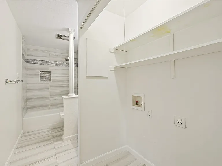 Bathroom featuring a full tub and shower combination with gray-toned tile surround, a built-in shower niche, and a contrasting mosaic tile accent band