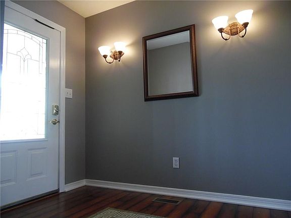 Welcoming foyer filled with natural light, wall sconce lighting, and new laminate hardwood.