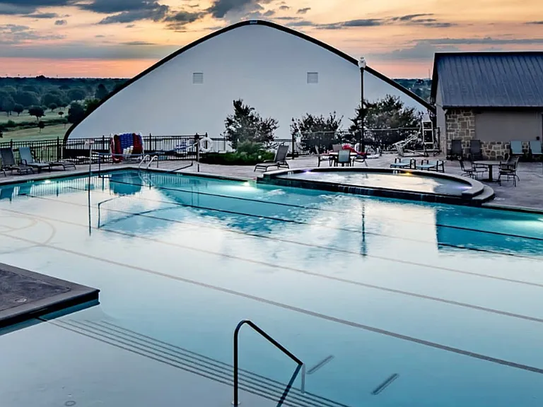 Expansive swimming pool area featuring a large main pool with lane markers, an integrated spa, and a separate smaller pool