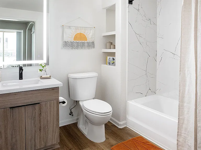 Apartment Bathroom with large soaking tub, LED vanity mirror and Wood Style Flooring.