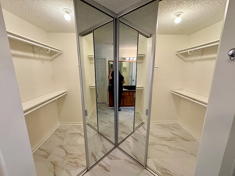 large walk-in, wraparound closet with double, full-length, mirrored doors