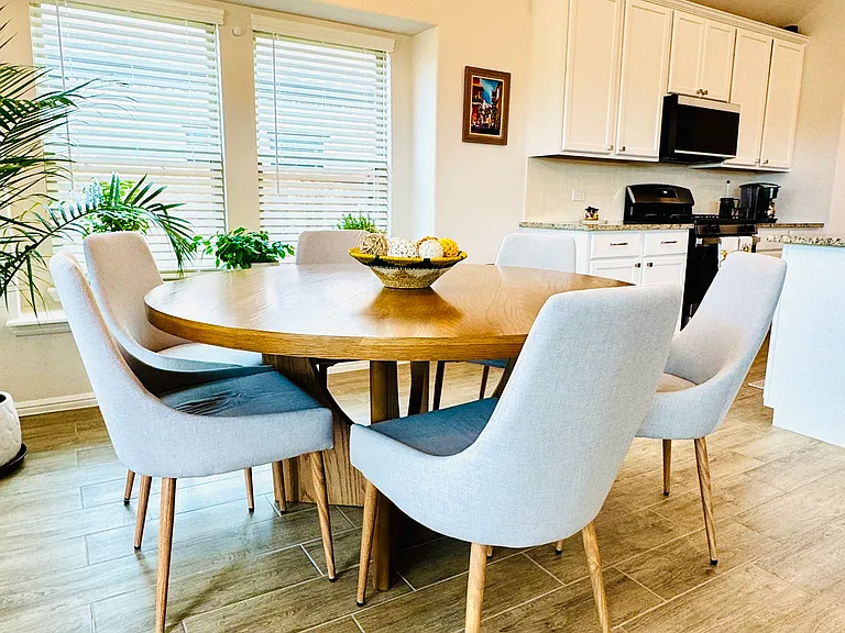 Elegant dining space featuring three large windows that flood the room with natural light, creating a warm and airy atmosphere. Perfectly positioned next to the kitchen, this beautiful area is ideal for both everyday dining and entertaining guests.