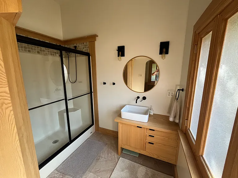 Updated bath on main floor includes dual-head shower, custom-built woodwork, and heated floors!