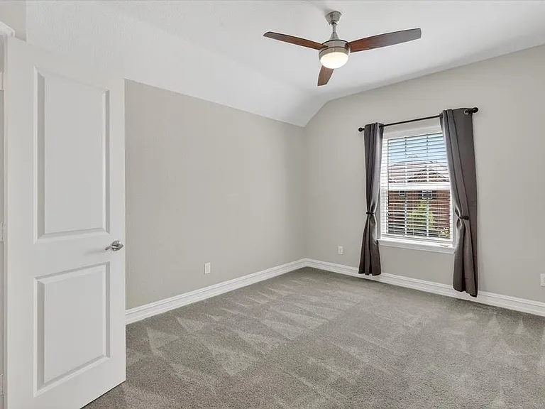 Carpeted room featuring a ceiling fan with integrated lighting, a window with blinds, and white trim
