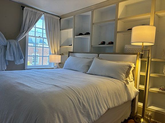 King Bed with custom built-in shelves. There are two windows in the bedroom and a window HVAC unit.