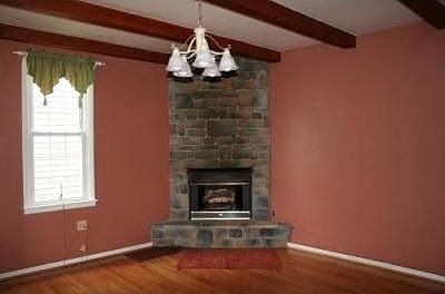 Cozy living room with beamed ceilings, Stone fireplace and hardwood floors  