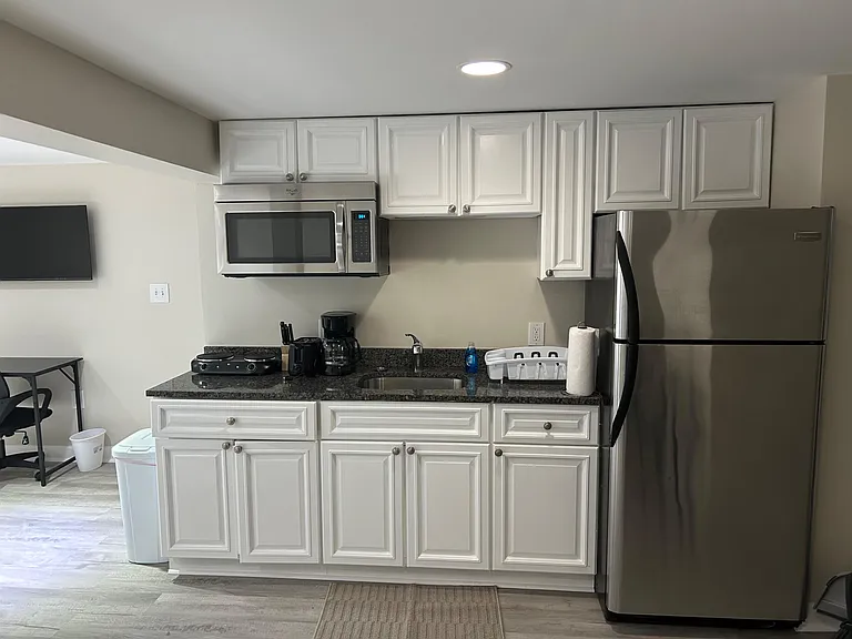 Efficient kitchen with ample white cabinetry, granite-look counters, stainless fridge, and built-in microwave over the sink.