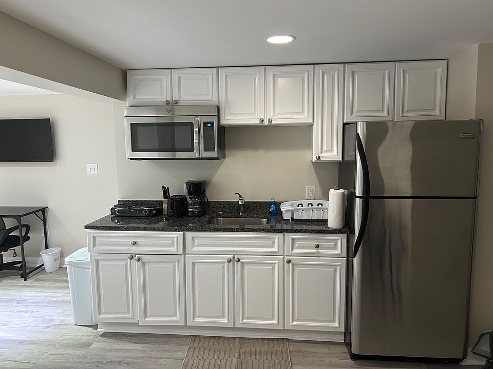 Efficient kitchen with ample white cabinetry, granite-look counters, stainless fridge, and built-in microwave over the sink.