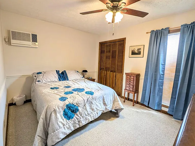 Furnished bedroom featuring a ceiling fan, carpeted floors, a window with curtains, and a closet for convenient storage.