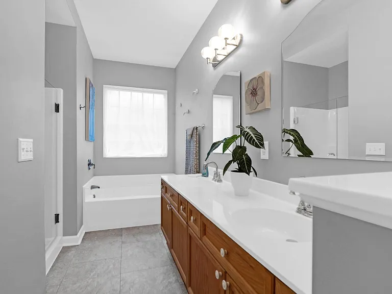 Attached primary bathroom with sunlit soaking tub, shower and double vanities.