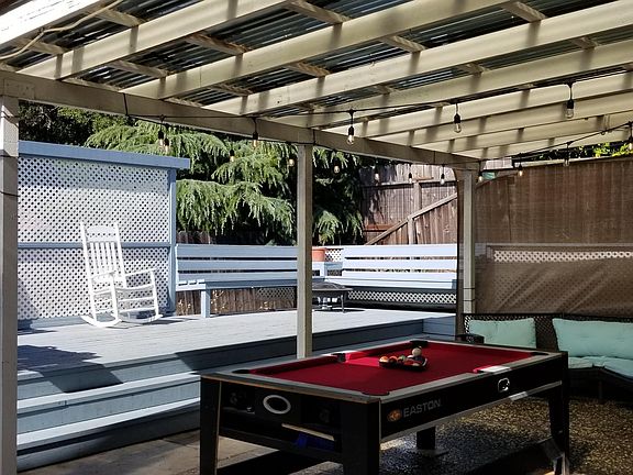 An oasis of a backyard includes beautiful deck, pool table hanging lights and patio furniture to entertain and enjoy
