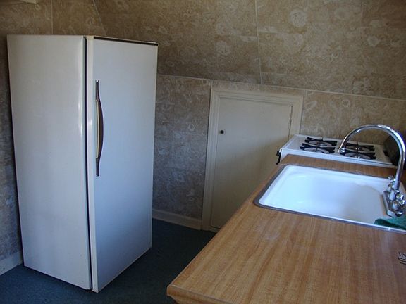 Kitchen with refrigerator and gas stove. Apartment entry is