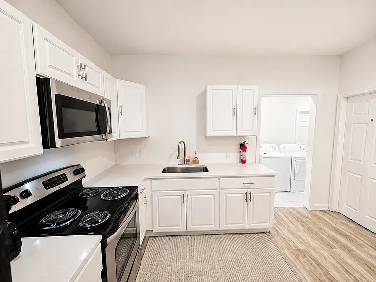 Efficient kitchen with generous cabinet storage, full-size range and microwave, and a handy adjacent laundry area.
