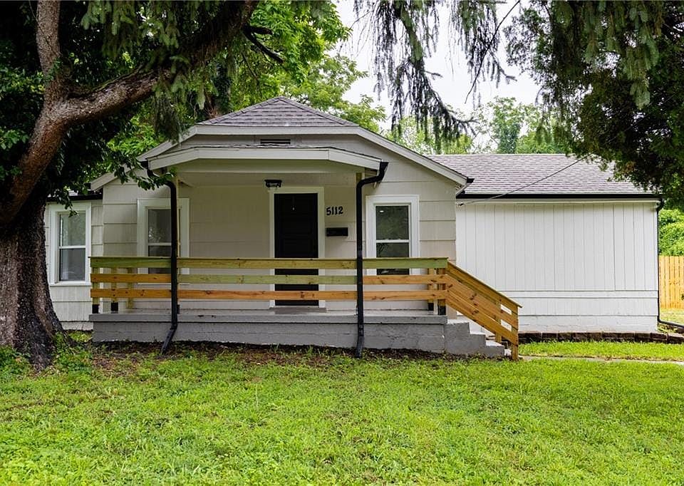 Light-toned siding exterior with a covered front porch featuring a wooden railing and steps