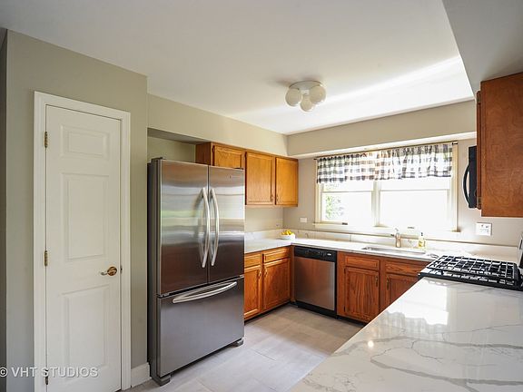 Updated kitchen has stainless appliances, quartz countertops, and a porcelain tile floor