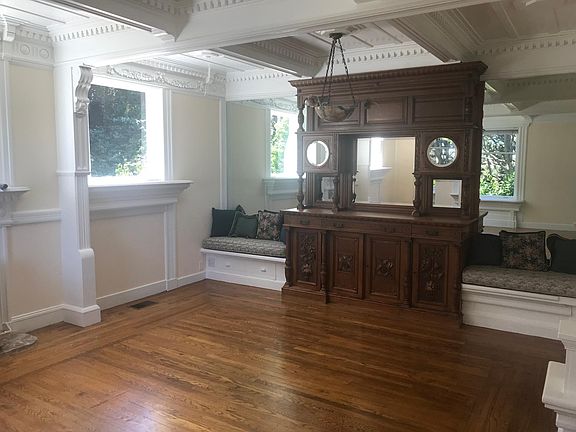 hardwood floor living room with hand carved china cabinet and 3 windows viewing private park