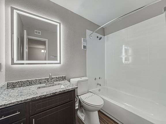 Updated one-bedroom apartment bathroom with granite vanity and modern lighting