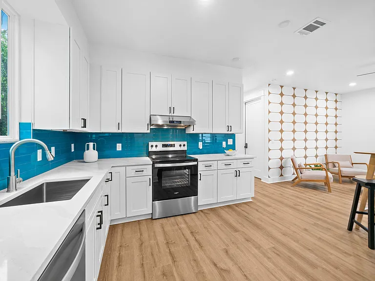 Updated kitchen with ample white cabinetry, stainless range, and generous counters, opening to an adjacent dining area.