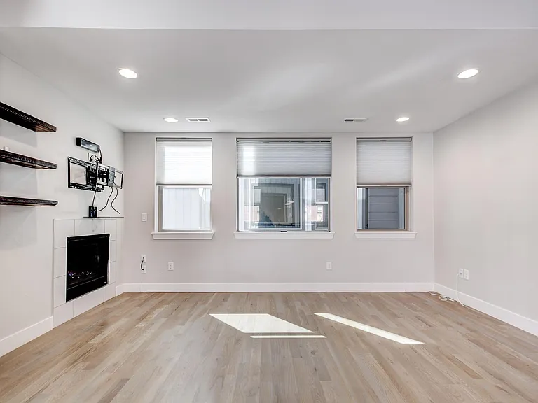 Living area with gas fireplace and privacy windows with blinds. TV wall mount and shelving.